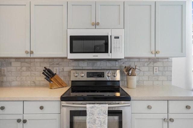 9961 SW Glenbrook Dr, Port Saint Lucie, FL 34987 - kitchen featuring stainless steel range with electric stovetop, white cabinets, light countertops, and white microwave