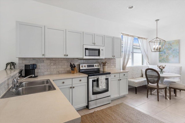 9961 SW Glenbrook Dr, Port Saint Lucie, FL 34987 - kitchen with light countertops, backsplash, a sink, stainless steel range with electric cooktop, and white microwave