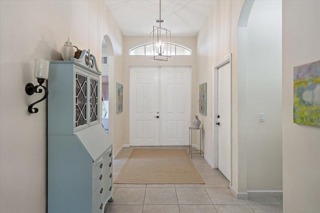 9961 SW Glenbrook Dr, Port Saint Lucie, FL 34987 - entrance foyer with arched walkways, a notable chandelier, baseboards, and light tile patterned floors