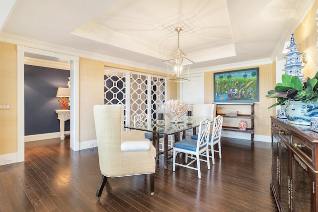 dining space with baseboards, a raised ceiling, an inviting chandelier, crown molding, and wood finished floors