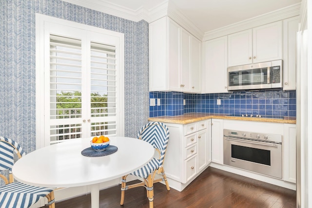 kitchen featuring tasteful backsplash, wallpapered walls, dark wood-style floors, white cabinetry, and appliances with stainless steel finishes