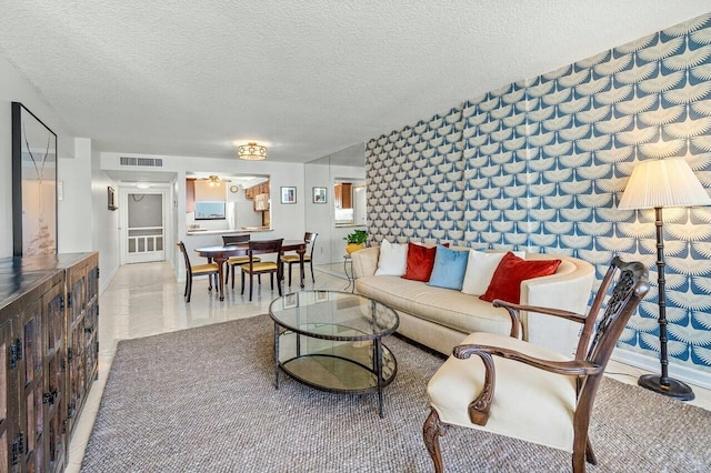 living area featuring baseboards, visible vents, and a textured ceiling