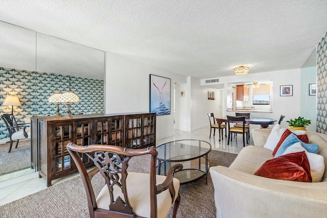 living room with a textured ceiling, visible vents, tile patterned flooring, and a ceiling fan