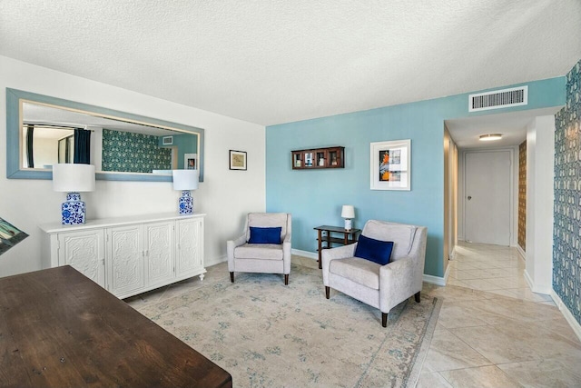 sitting room with visible vents, a textured ceiling, and light tile patterned floors
