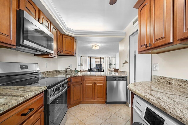 kitchen with light tile patterned flooring, brown cabinets, appliances with stainless steel finishes, and washer / dryer