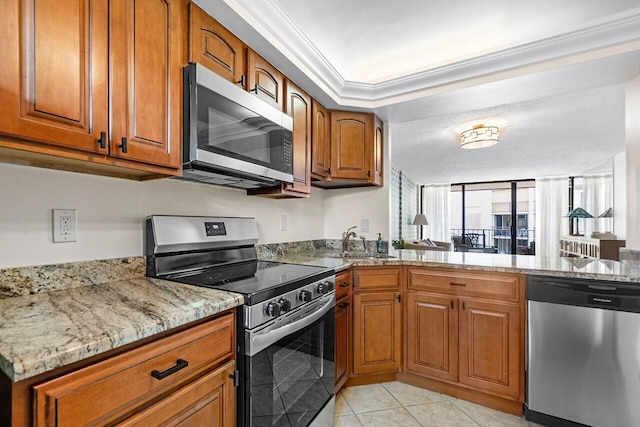 kitchen with brown cabinets, light stone countertops, appliances with stainless steel finishes, and a sink