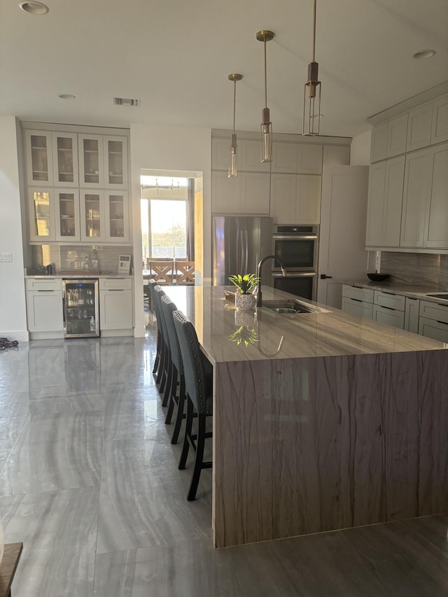 1071 S Header Canal Rd, Fort Pierce, FL 34945 - kitchen with wine cooler, stainless steel appliances, backsplash, a sink, and light stone counters