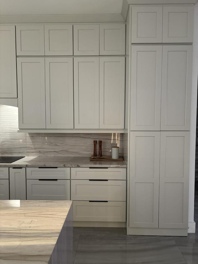 1071 S Header Canal Rd, Fort Pierce, FL 34945 - kitchen featuring white cabinetry, tasteful backsplash, light stone counters, and black electric stovetop