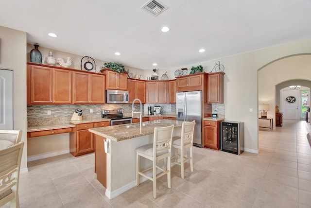 7147 Prudencia Dr, Lake Worth, FL 33463 - kitchen featuring stainless steel appliances, beverage cooler, a sink, arched walkways, and tasteful backsplash