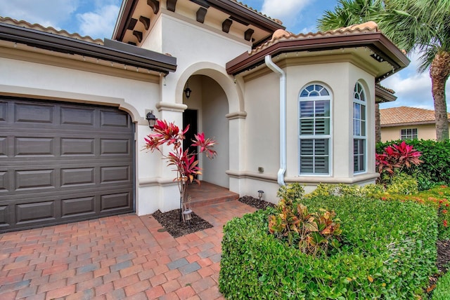 7147 Prudencia Dr, Lake Worth, FL 33463 - doorway to property featuring stucco siding, a tile roof, decorative driveway, and a garage