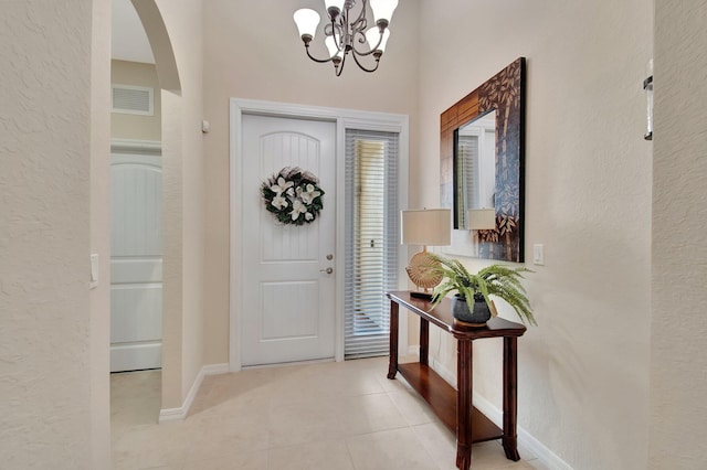 7147 Prudencia Dr, Lake Worth, FL 33463 - foyer entrance with a chandelier, arched walkways, light tile patterned floors, a textured wall, and baseboards