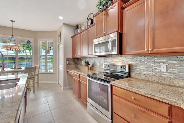 7147 Prudencia Dr, Lake Worth, FL 33463 - kitchen featuring stainless steel appliances, baseboards, tasteful backsplash, light tile patterned flooring, and decorative light fixtures