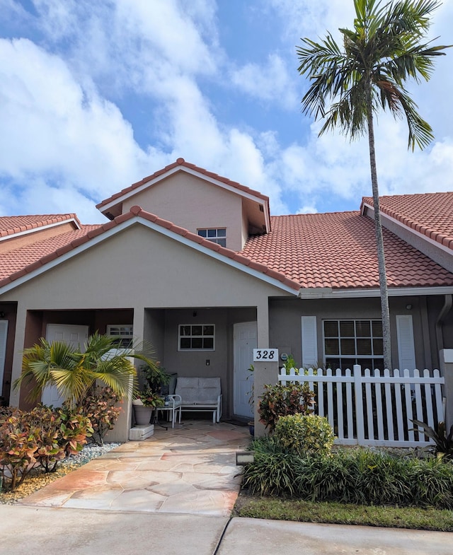 view of front of property featuring fence, stucco siding, and a tiled roof