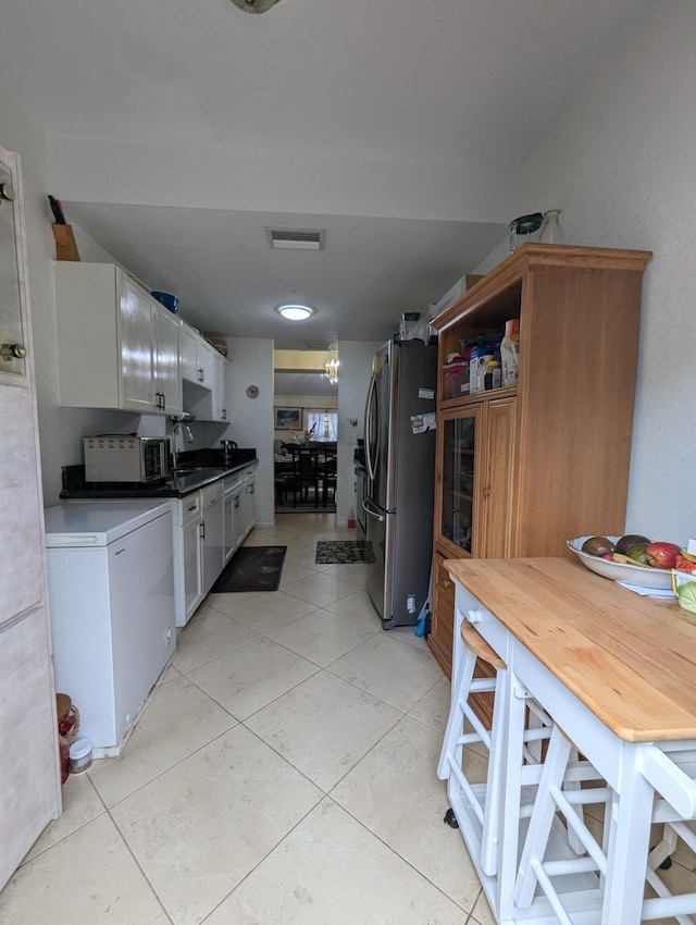 kitchen featuring light tile patterned flooring, a sink, refrigerator, freestanding refrigerator, and visible vents