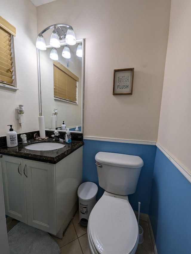 half bath featuring toilet, tile patterned flooring, and vanity