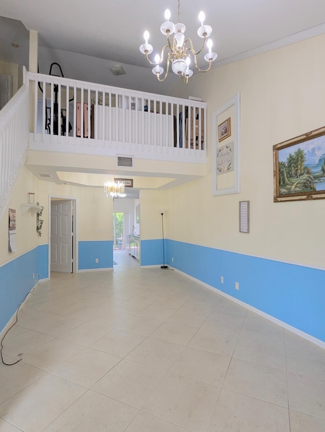 tiled spare room with a high ceiling, baseboards, visible vents, and a notable chandelier