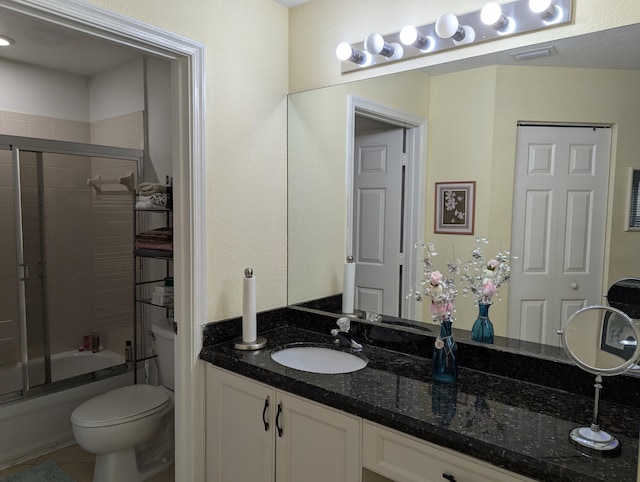 full bath featuring combined bath / shower with glass door, toilet, tile patterned flooring, and vanity