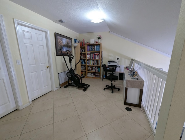 tiled office space featuring vaulted ceiling, visible vents, and a textured ceiling