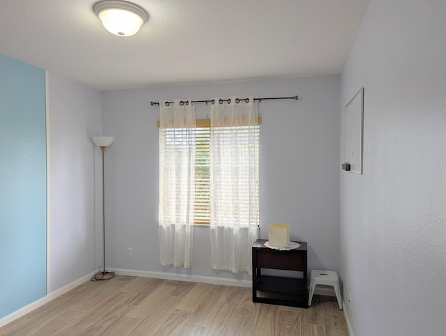 spare room with baseboards and wood finished floors
