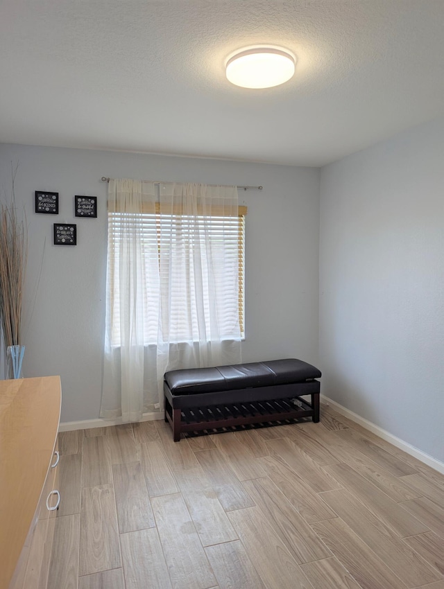 living area with a textured ceiling, baseboards, and wood finished floors
