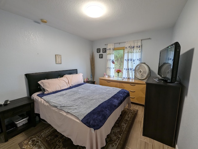 bedroom with a textured ceiling and wood finish floors