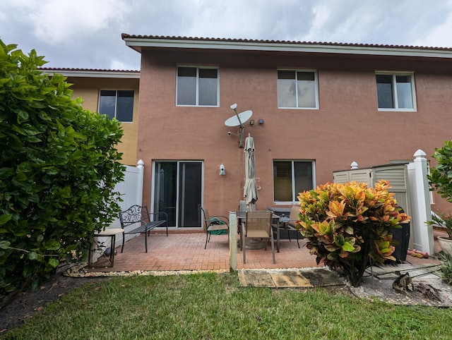 back of property with a tile roof, stucco siding, and a patio area