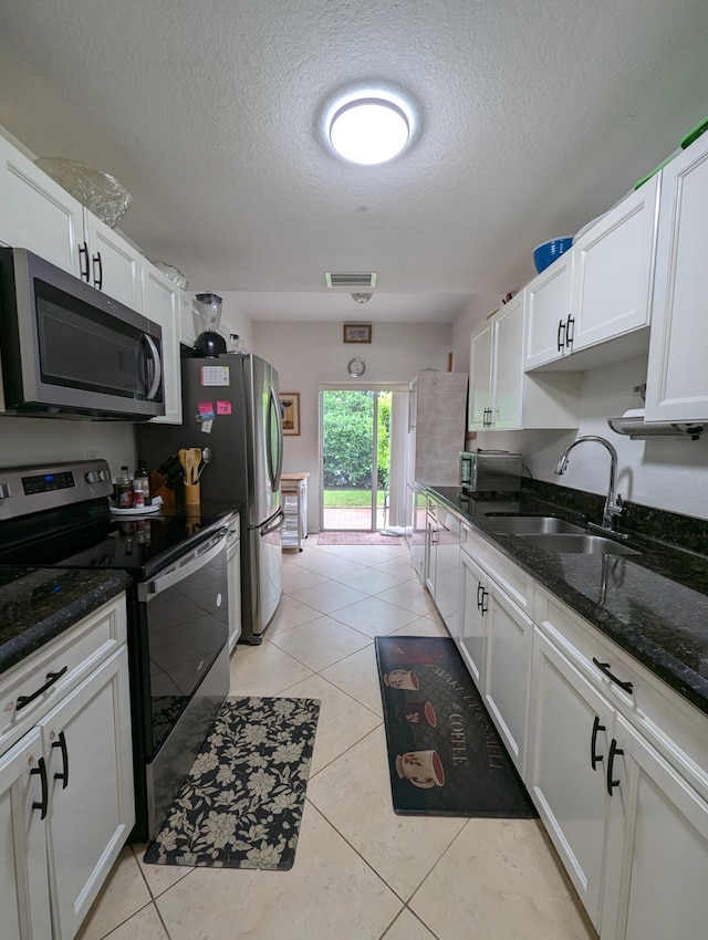 kitchen with white cabinetry, light tile patterned floors, a sink, visible vents, and appliances with stainless steel finishes