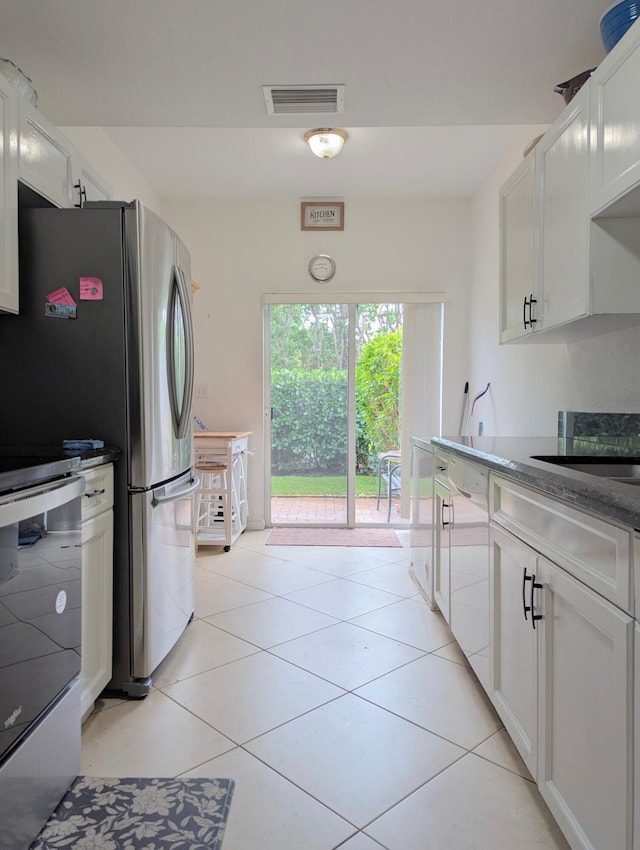 kitchen with dishwashing machine, visible vents, light tile patterned flooring, and range