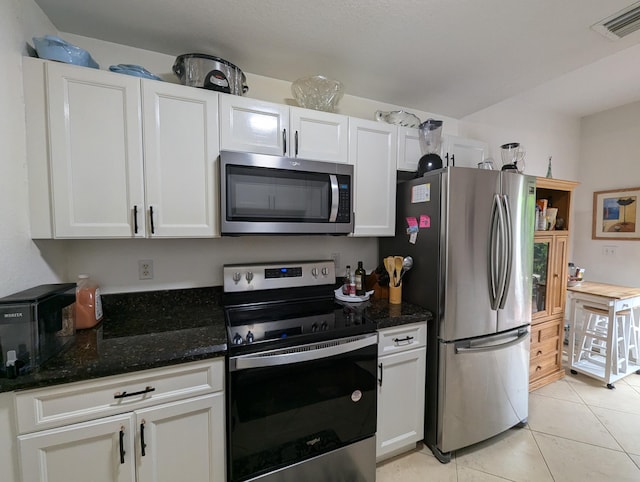 kitchen with light tile patterned flooring, visible vents, white cabinetry, and stainless steel appliances