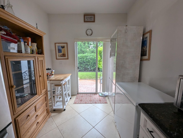 interior space with refrigerator and light tile patterned floors