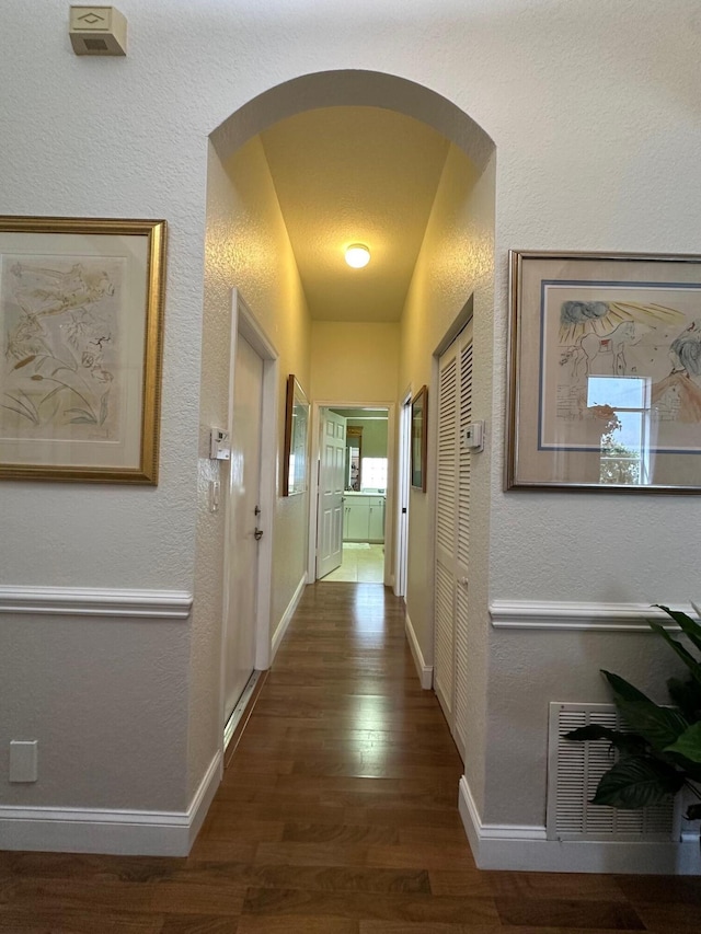 3112 Bollard Rd, West Palm Beach, FL 33411 - corridor featuring wood finished floors, arched walkways, a textured wall, and baseboards