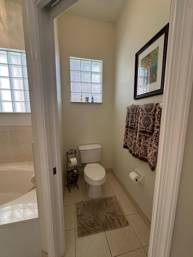 3112 Bollard Rd, West Palm Beach, FL 33411 - bathroom featuring toilet, a garden tub, and tile patterned floors