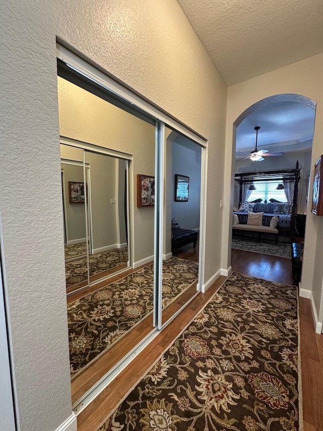3112 Bollard Rd, West Palm Beach, FL 33411 - hallway featuring wood finished floors, a textured wall, arched walkways, and a textured ceiling