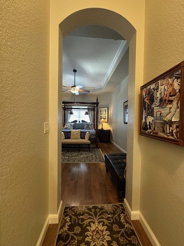 3112 Bollard Rd, West Palm Beach, FL 33411 - hallway featuring arched walkways, a textured wall, wood finished floors, and baseboards