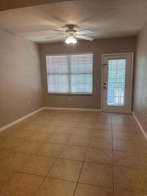 162 SW Peacock Blvd Unit 205, Port Saint Lucie, FL 34986 - unfurnished room with plenty of natural light, light tile patterned floors, a ceiling fan, a textured ceiling, and baseboards