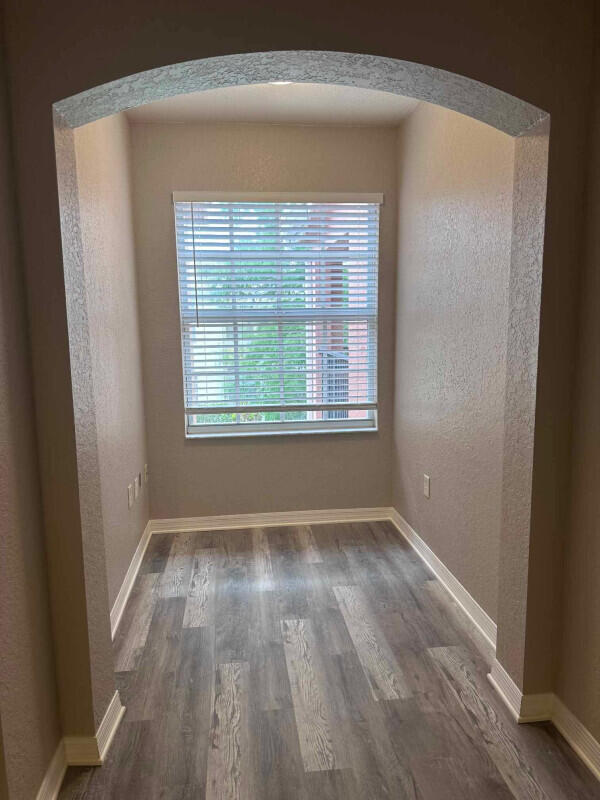 162 SW Peacock Blvd Unit 205, Port Saint Lucie, FL 34986 - unfurnished room with arched walkways, wood finished floors, a textured wall, and baseboards