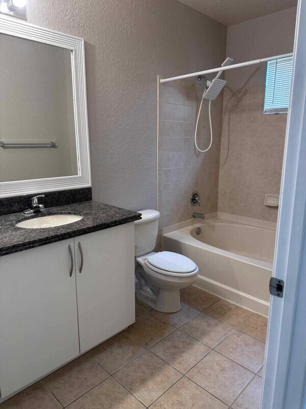 162 SW Peacock Blvd Unit 205, Port Saint Lucie, FL 34986 - full bathroom with vanity, bathing tub / shower combination, toilet, tile patterned flooring, and a textured wall