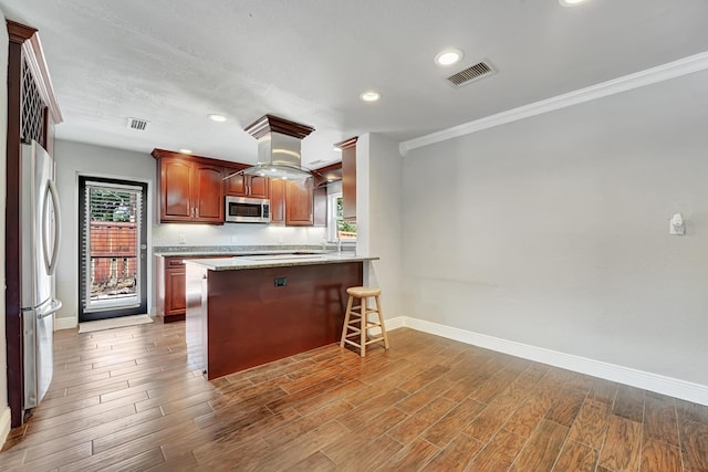 kitchen with a breakfast bar, stainless steel appliances, baseboards, ornamental molding, and visible vents