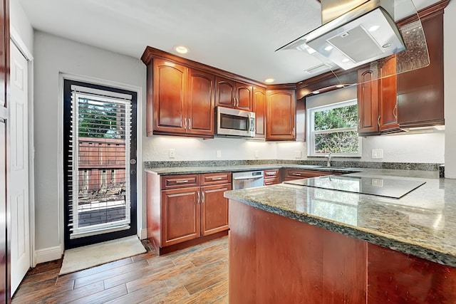 kitchen with recessed lighting, stainless steel appliances, extractor fan, light wood-style floors, and dark stone counters