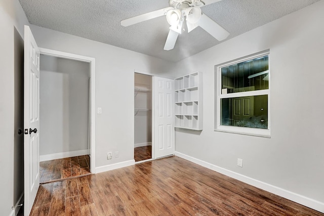 unfurnished bedroom featuring baseboards, wood finished floors, a textured ceiling, and a closet