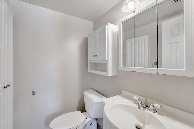 half bath featuring toilet and a sink