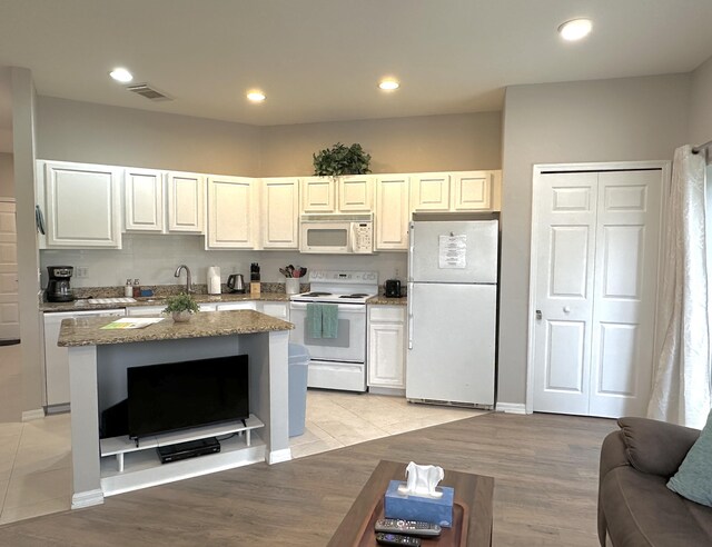 9851 Perfect Dr Unit 151, Port Saint Lucie, FL 34986 - kitchen with white appliances, light stone counters, light wood-style floors, recessed lighting, and a center island
