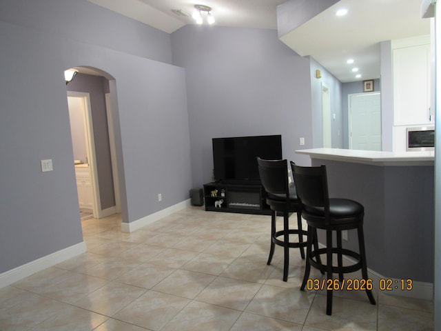 443 SW Homeland Rd, Port Saint Lucie, FL 34953 - kitchen featuring light countertops, a breakfast bar, light tile patterned floors, white cabinets, and arched walkways