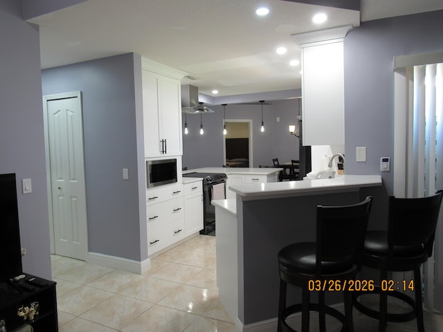 443 SW Homeland Rd, Port Saint Lucie, FL 34953 - kitchen featuring white cabinetry, a breakfast bar, a peninsula, stainless steel microwave, and black / electric stove