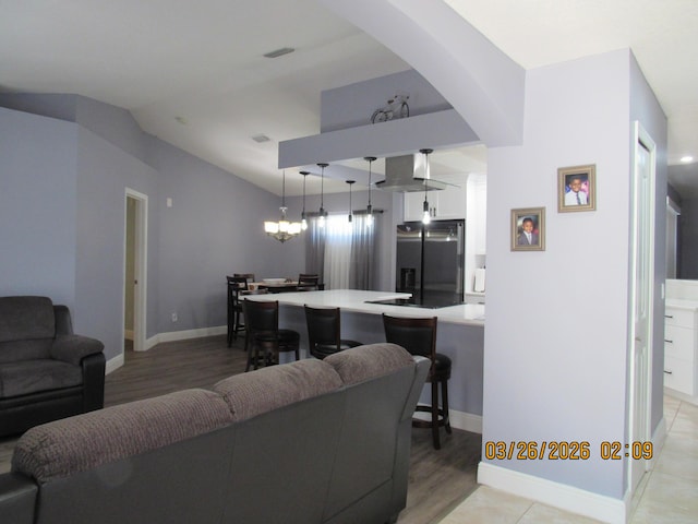 443 SW Homeland Rd, Port Saint Lucie, FL 34953 - living area with visible vents, baseboards, arched walkways, light wood-style floors, and vaulted ceiling