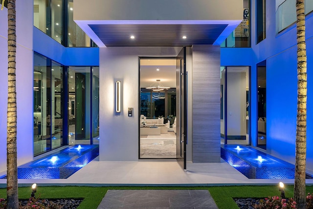 372 E Alexander Palm Rd, Boca Raton, FL 33432 - doorway to property with a jacuzzi, stucco siding, and an infinity pool