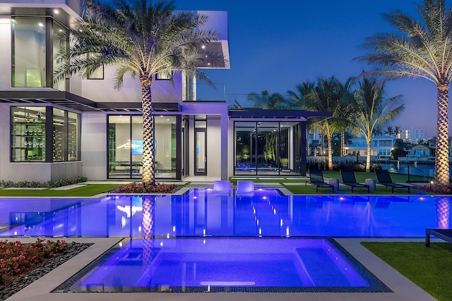 372 E Alexander Palm Rd, Boca Raton, FL 33432 - back of house at night with an outdoor pool, an in ground hot tub, and stucco siding