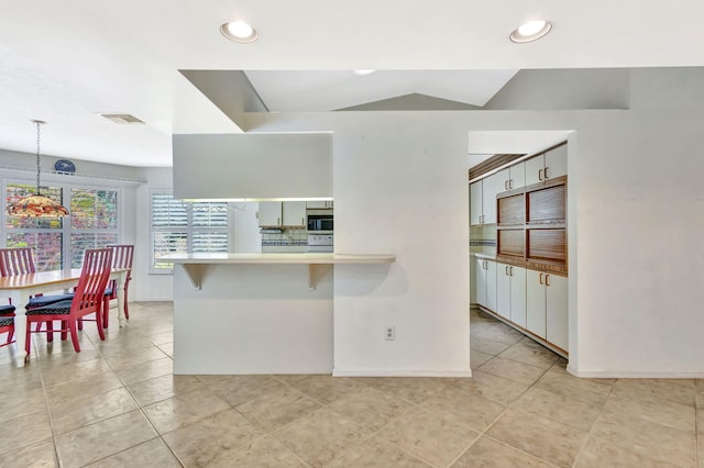 2101 SE Harlow St, Port Saint Lucie, FL 34952 - kitchen with light tile patterned floors, visible vents, stainless steel microwave, and pendant lighting