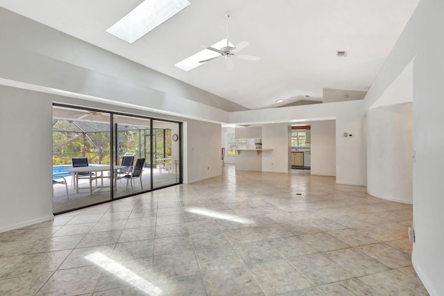 2101 SE Harlow St, Port Saint Lucie, FL 34952 - unfurnished living room with baseboards, ceiling fan, and vaulted ceiling with skylight