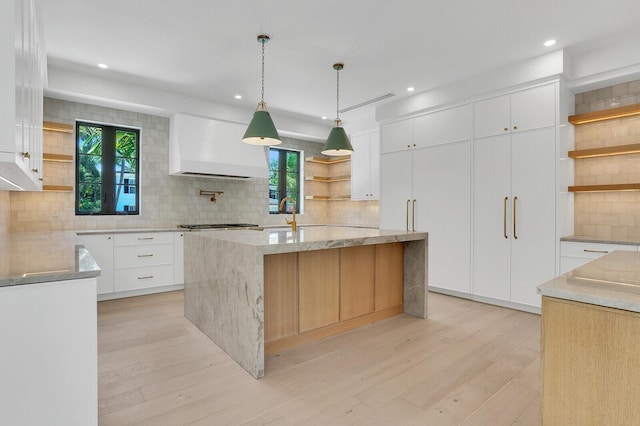 3408 Washington Rd, West Palm Beach, FL 33405 - kitchen featuring open shelves, custom range hood, decorative backsplash, light wood-type flooring, and light stone counters